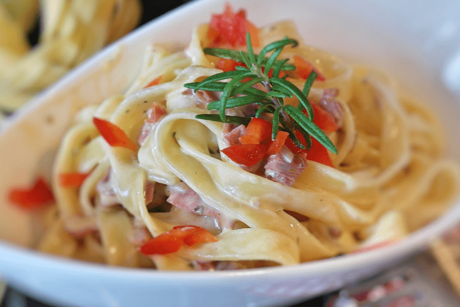 Creamy salmon linguine with diced red pepper in a bowl