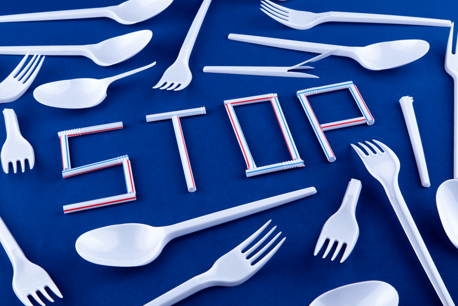 White single-use plastic cutlery and the word stop on a blue background. Photo by Volodymyr Hryshchenko on Unsplash
