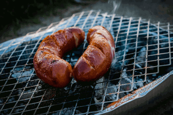 Two sausages on charcoal barbeque