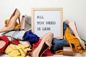 Sign saying "All you need is less", surrounded by clothes and shoes.