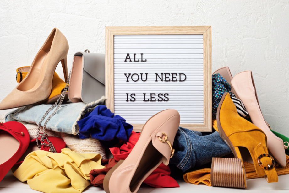 Sign saying "All you need is less", surrounded by clothes and shoes.